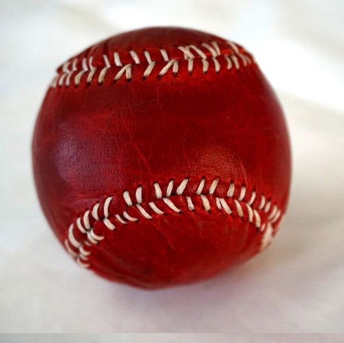 Handmade vintage red leather baseball sewn with thread and needle, crafted by DAVISCASE for a classic, artisanal look.