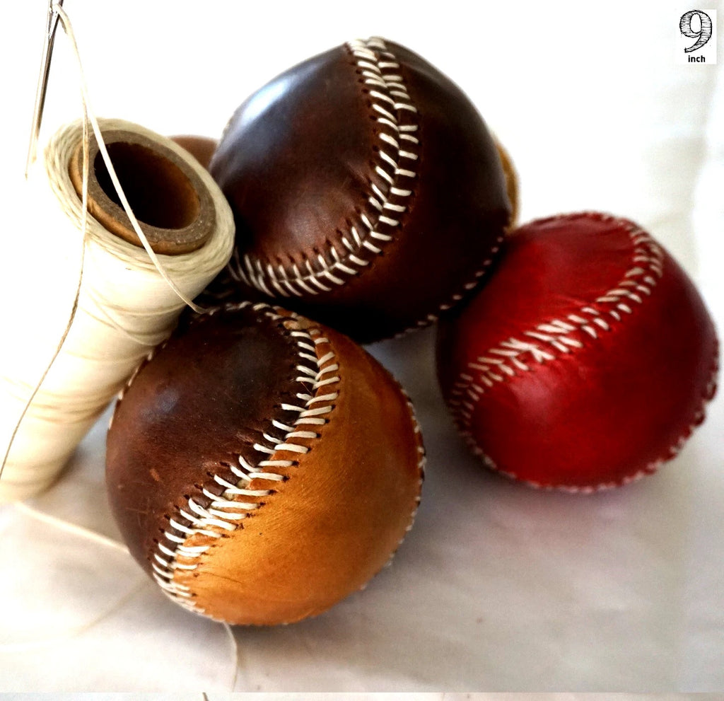 Handmade vintage red leather baseball sewn with thread and needle, crafted by DAVISCASE, showcasing detailed stitching and craftsmanship.