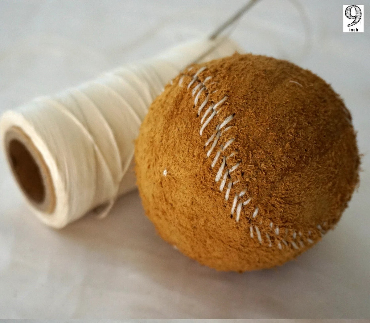 Handmade vintage red leather baseball sewn with thread and needle, crafted by DAVISCASE for a classic, artisanal look.