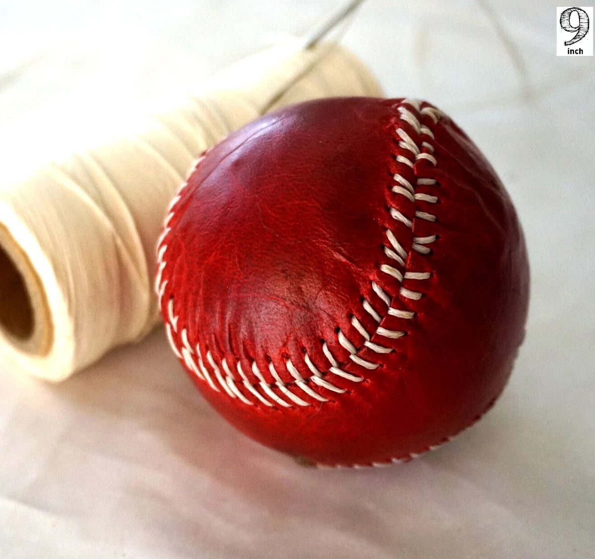 Handmade vintage red leather baseball with sewing thread and needle, crafted by DAVISCASE for a classic, artisanal look